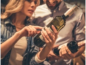 Couple looking at bottles of wine.