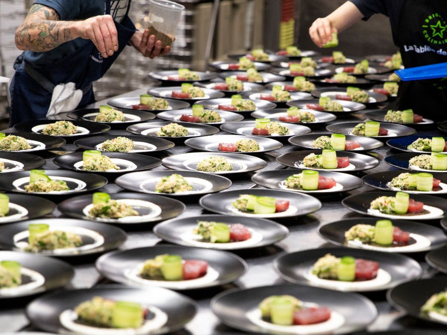 Image of a chef finalizing a series of plates before serving a meal