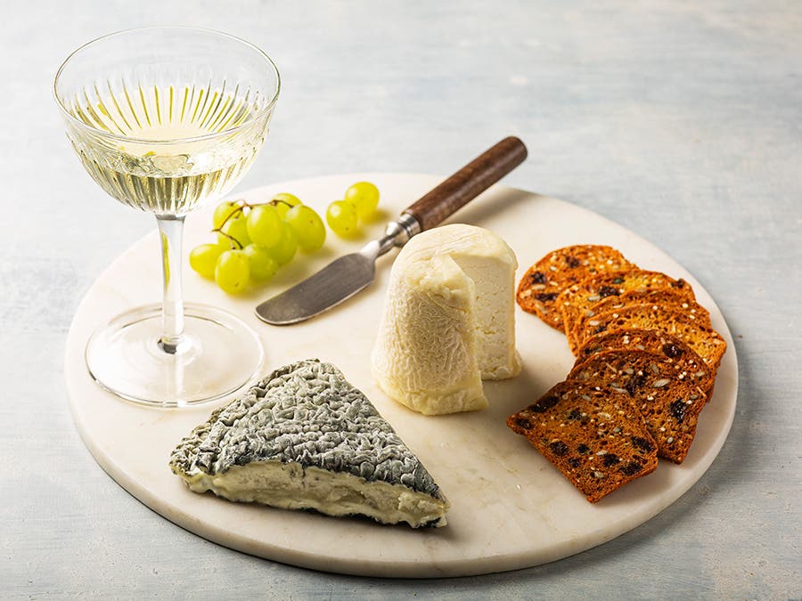 Cheese and mead pairing A tray with two goat cheeses, grapes, crackers and a glass of mead